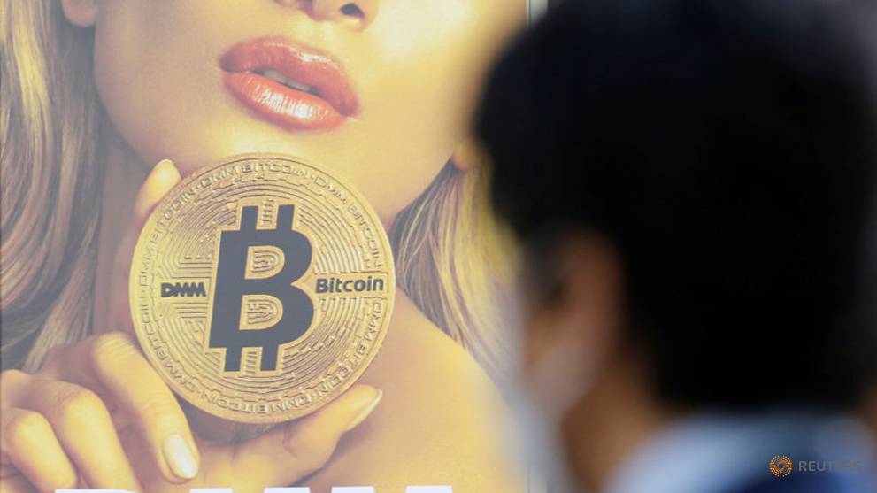 a-man-stands-near-an-advertisement-of-a-cryptocurrency-exchange-in-tokyo-1.jpg